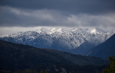 白天多云的天空下被雪覆盖的山